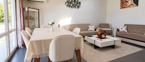 Ein modernes Wohnzimmer mit Esstisch, Sofa und Couchtisch.