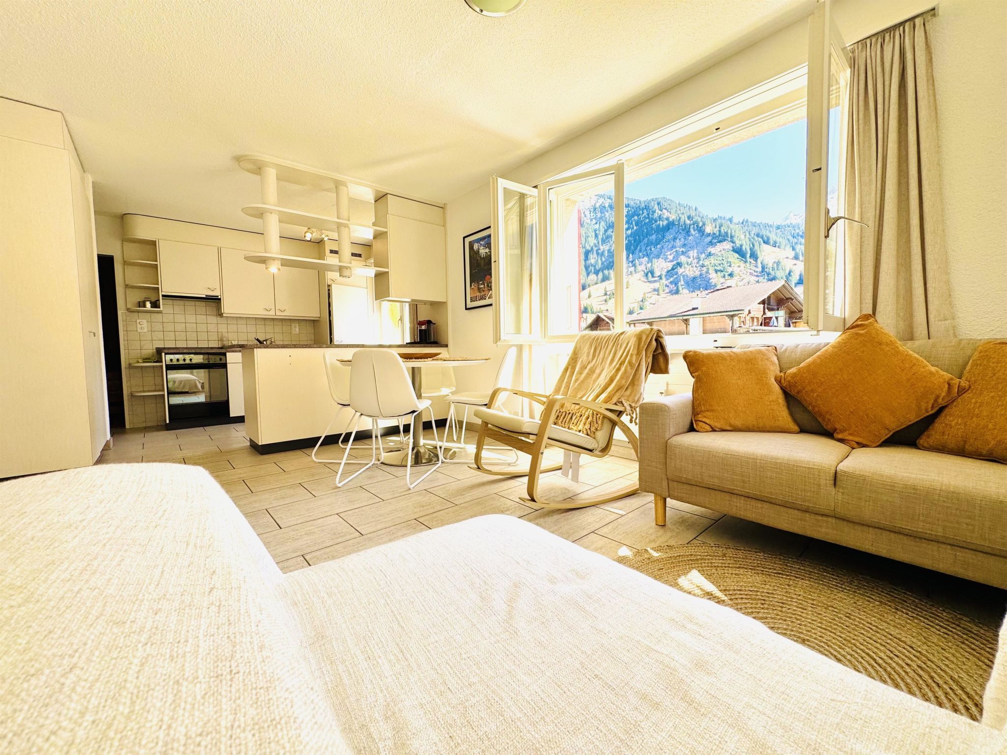 Een hotelkamer met een bed, een slaapbank, een stoel, een bureau en uitzicht op een bergachtig landschap.