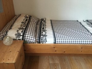A wooden bed with a checkered bedspread and matching pillows. - Elim Appartement/Fewo, Bad, WC, 4 oder mehr Schlafräume 5.5 Zimmerwohnung by Interhome (Adelboden)