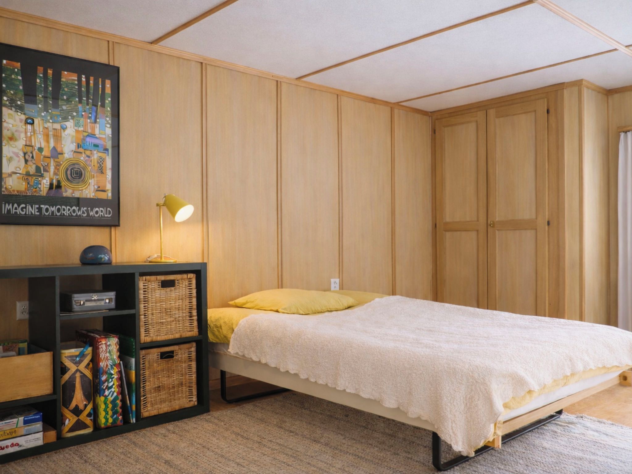 Une chambre à coucher avec un lit, un bureau doté d’une lampe et un tableau accroché au mur.