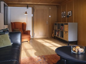 A cozy living room with a leather sofa, a wooden bookshelf, and a small round table with a glass container. - Bütschelshus Appartement/Fewo, Dusche und Bad, WC, 4 oder mehr Schlafräume by Interhome (Kandersteg)