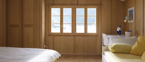 A room with two beds, a desk, a chair, and a window with a view.