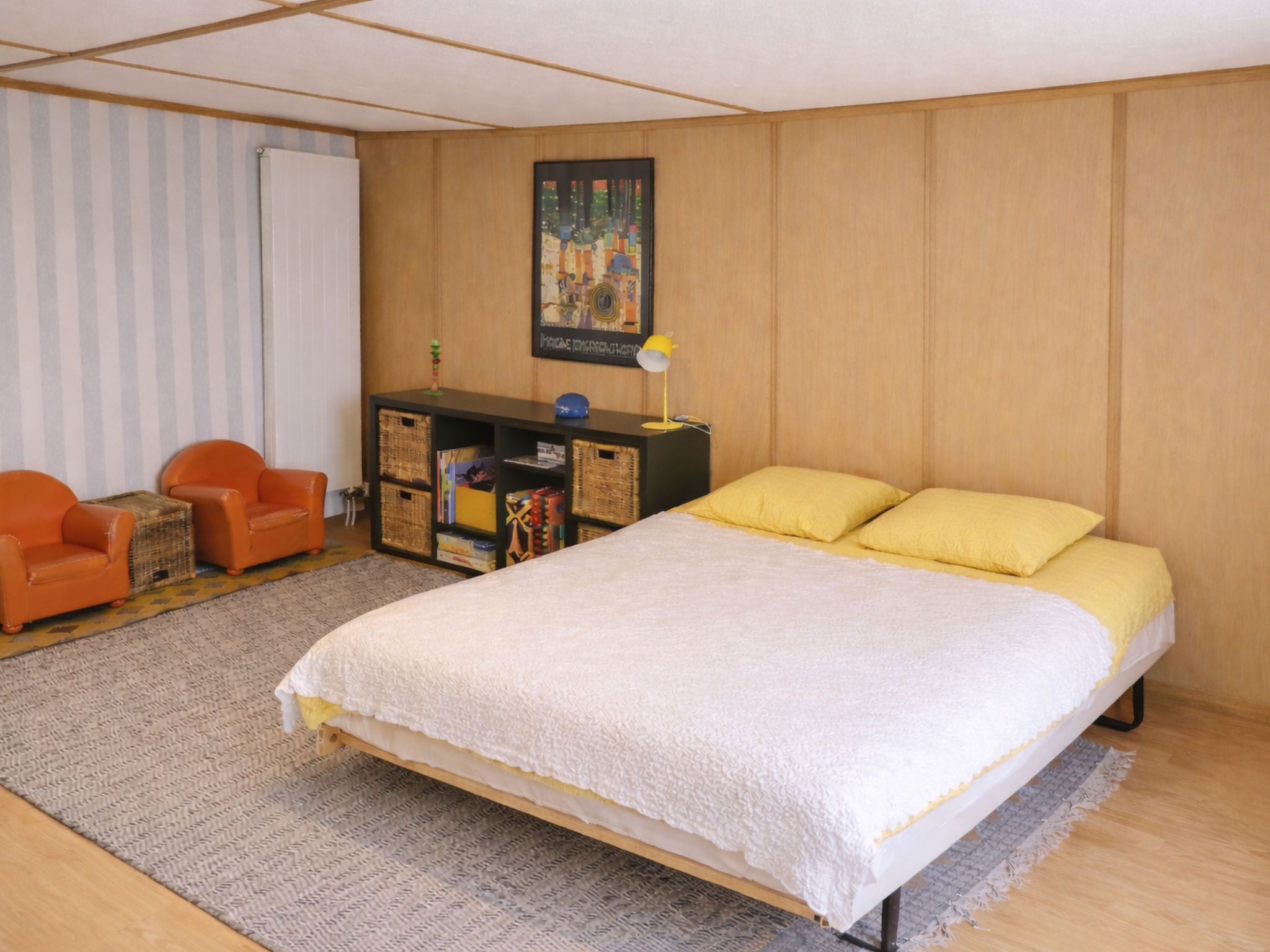 Une chambre à coucher avec un lit, un bureau, une chaise et un tableau au mur.