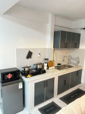 A compact kitchen with a microwave, stove, and sink.
