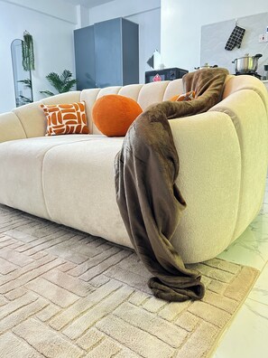 A living room with a sofa, a brown throw blanket, and a patterned rug.