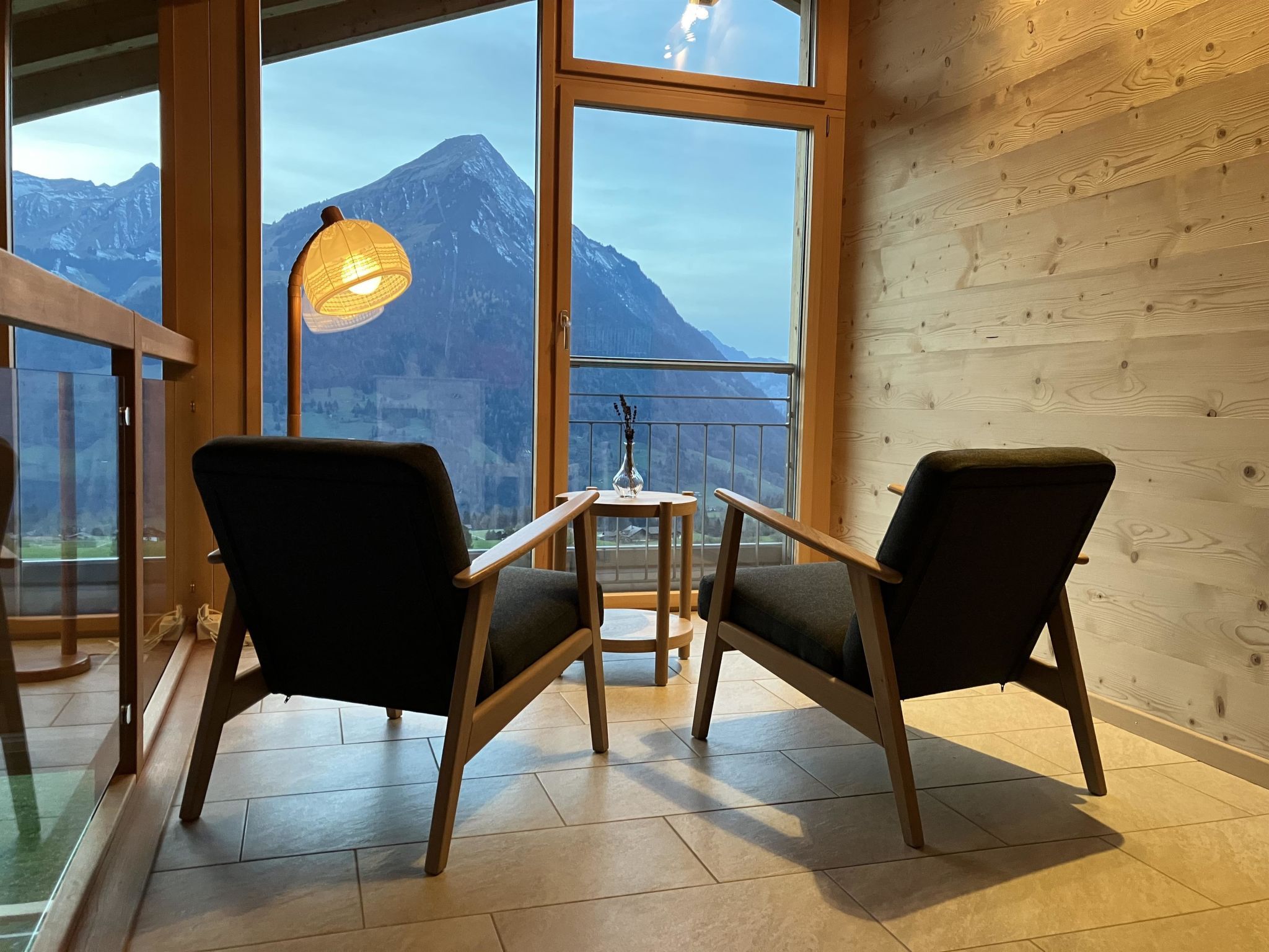 Una habitación con dos sillas frente a un ventanal con vistas a una montaña.