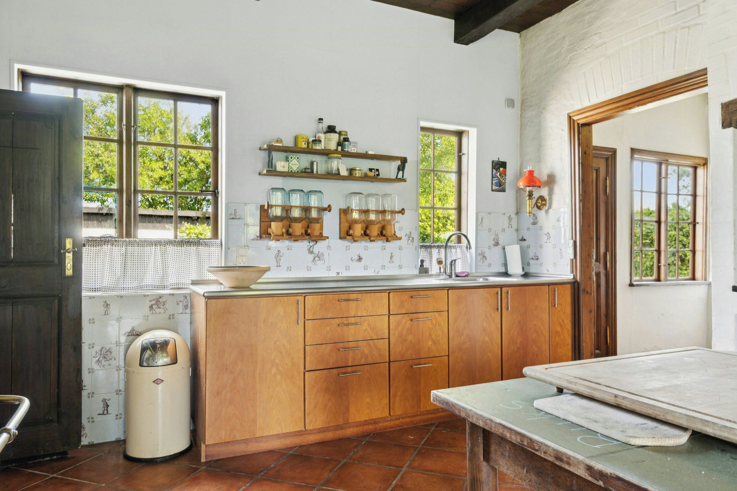 Una cocina con armarios de madera, salpicadero de azulejos y ventana con vistas a zonas verdes.