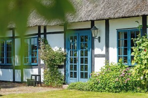 A traditional house with a thatched roof, blue doors, and white walls. - Village school from 1777 in West Lolland (Vesterborg)