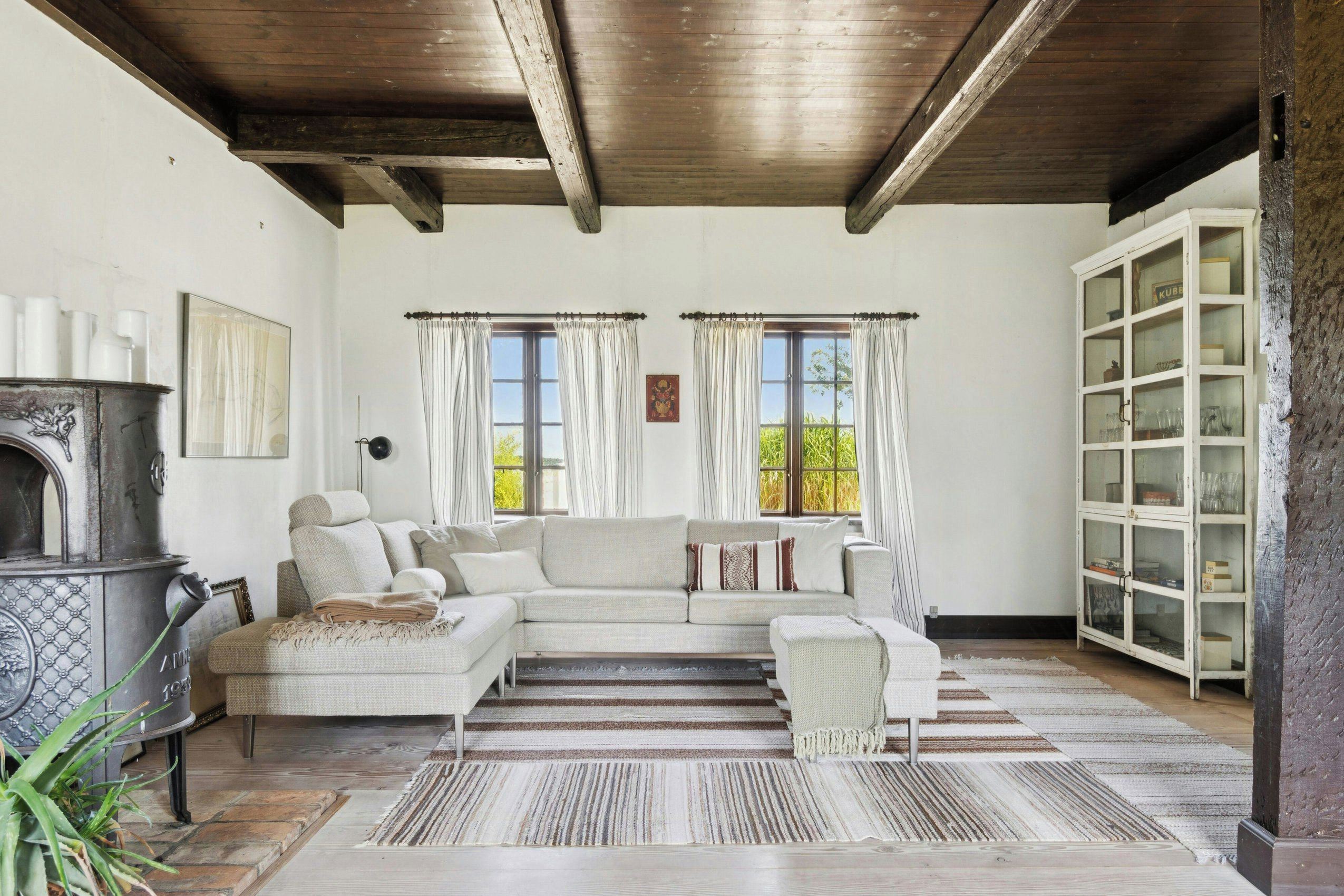 A living room with a sectional sofa, a fireplace, and a cabinet with glass doors.