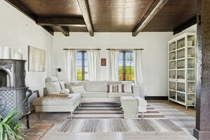 A living room with a sectional sofa, a fireplace, and a cabinet with glass doors. - Village school from 1777 in West Lolland (Vesterborg)