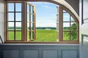 A room with a large arched window overlooking a green field. - Village school from 1777 in West Lolland (Vesterborg)