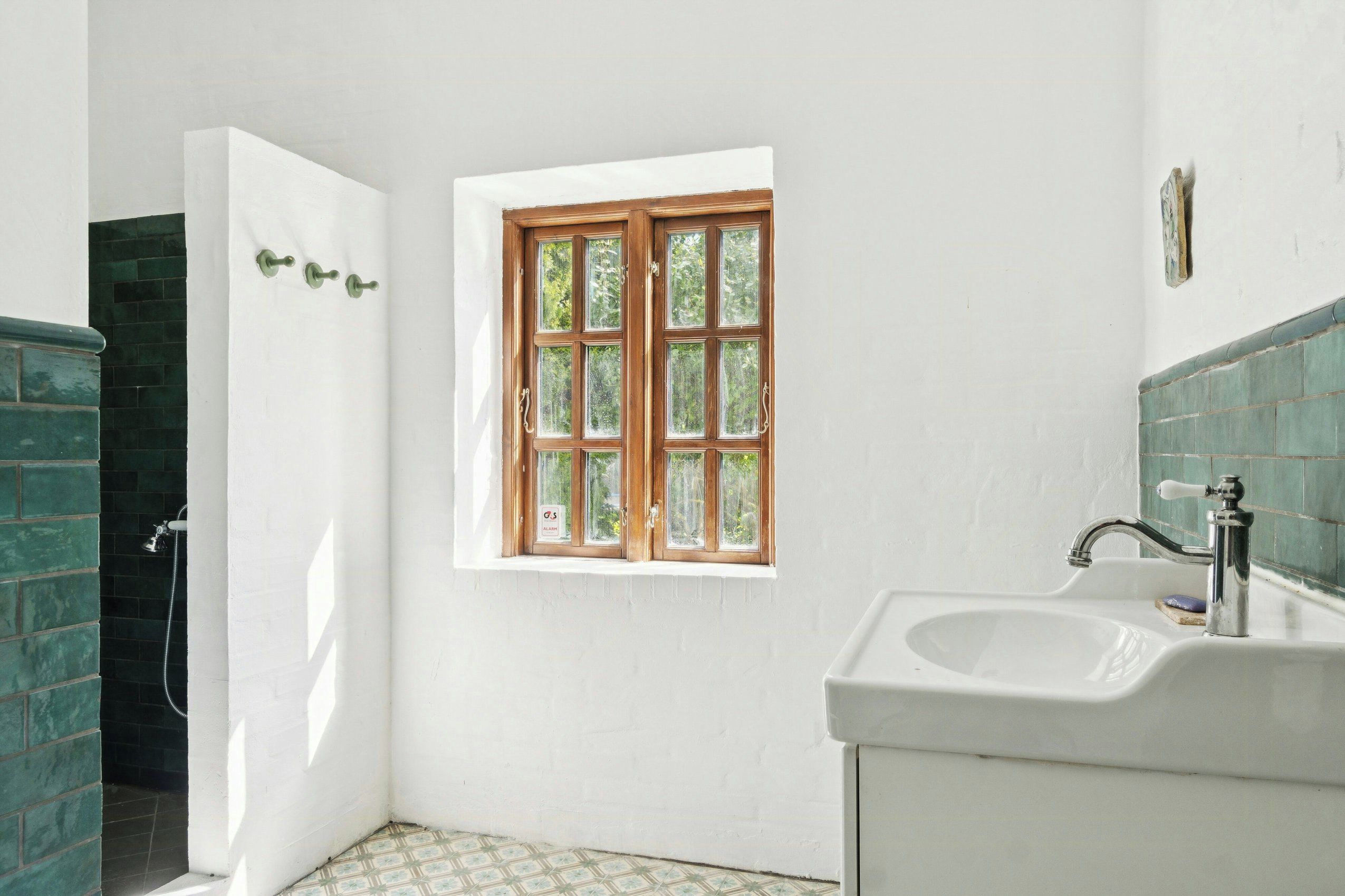 Un baño con ventana, lavabo y ducha.