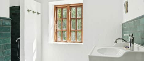 Un baño con ventana, lavabo y ducha.