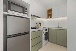 A compact kitchen with a refrigerator, microwave, and washing machine. - Asriya by Kozystay - Paskal (Bandung)