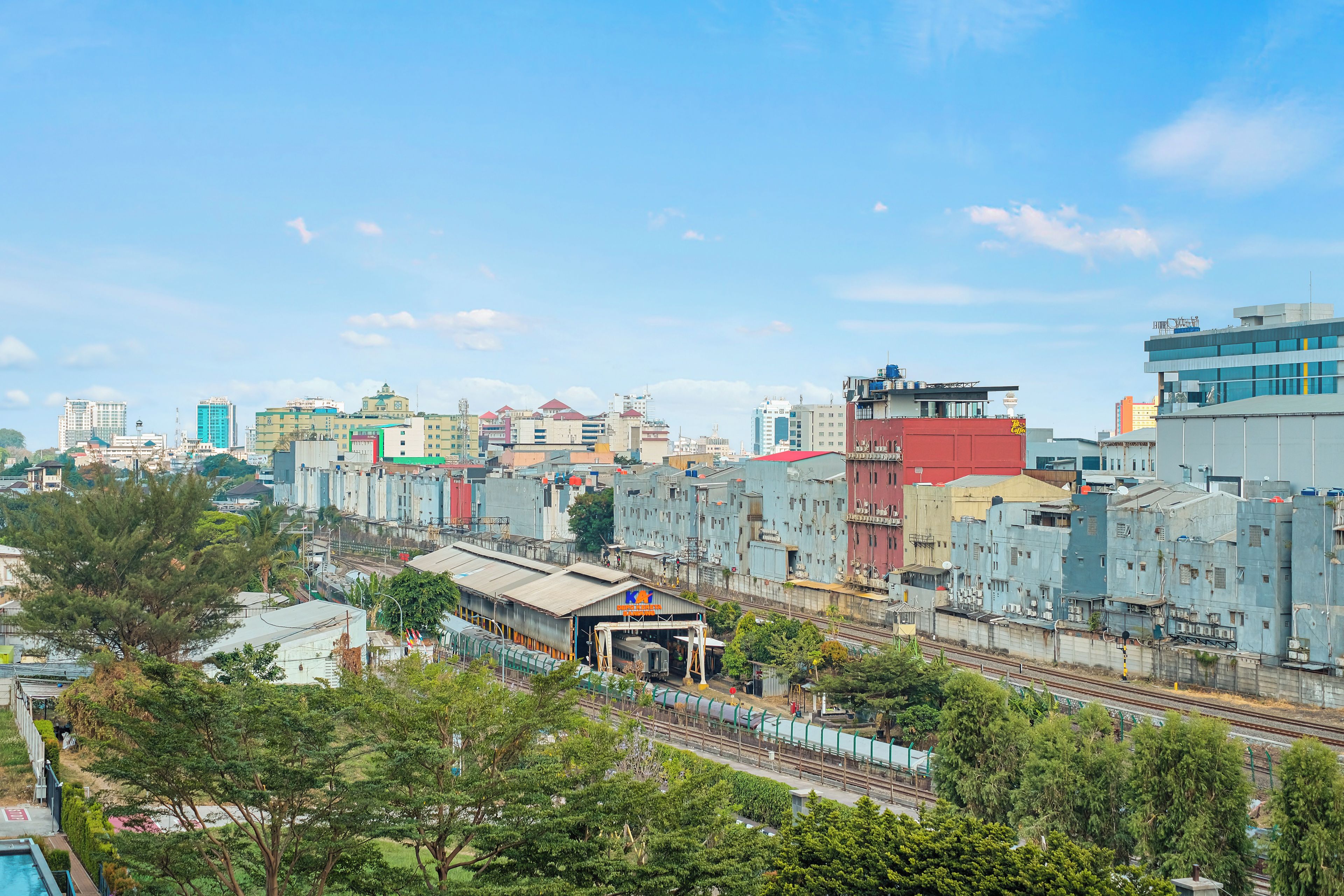 Un paisaje urbano con edificios industriales, una vía de tren y zonas verdes.