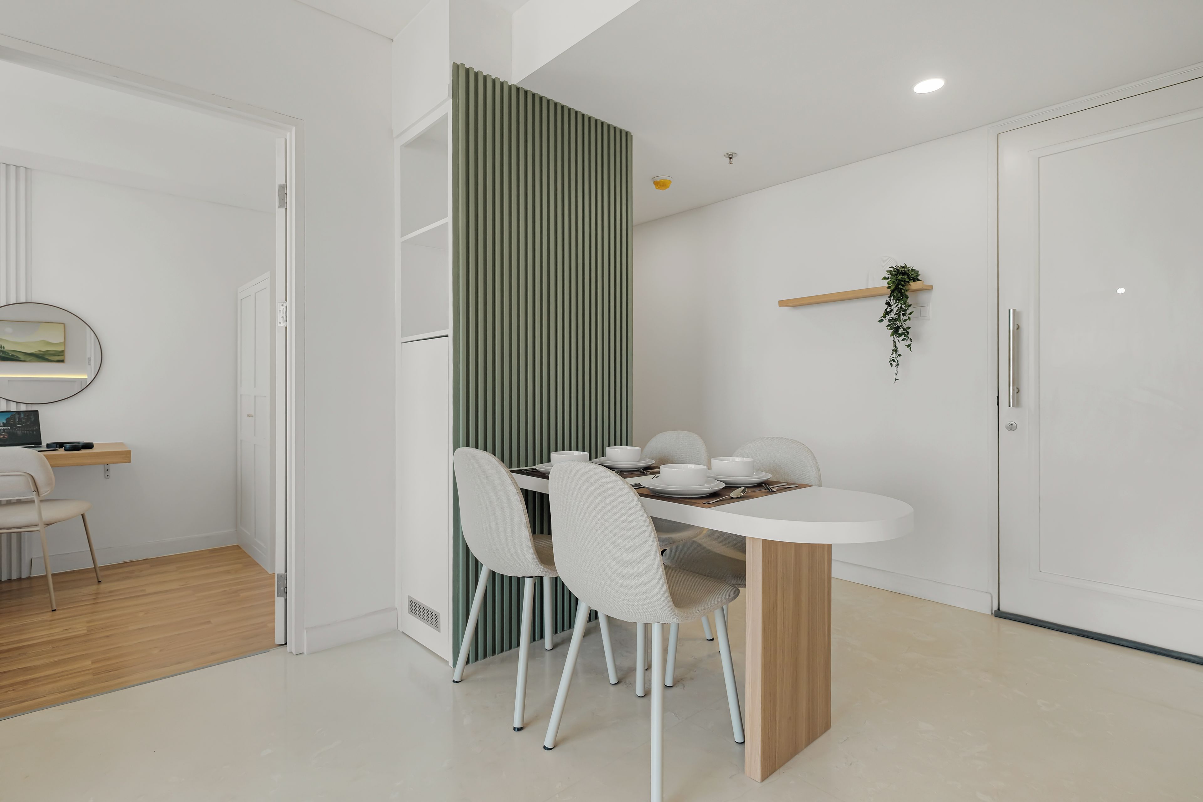 Un comedor moderno con una mesa blanca, cuatro sillas y una pared de acento verde.