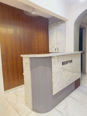 A reception desk with a marble top and a wooden panel wall. - Hotel PLAN SKY (Ahmedabad)