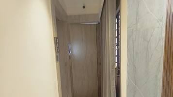 A hallway with a marble floor, a wooden door, and a wall with a marble pattern.