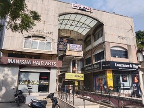 A building with multiple storefronts including Manisha Hair Arts, Hotel Plan Sky, and Lawrence & Mayo. - Hotel PLAN SKY (Ahmedabad)