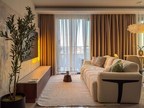 A modern living room with a sofa, a coffee table, and a potted plant. - Qoople Elize 68 - 2-bedroom Duplex in Alanya (Alanya)
