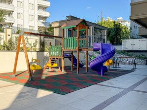 A playground with a slide, swings, and a climbing structure. - Qoople Elize 68 - 2-bedroom Duplex in Alanya (Alanya)