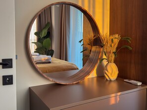 A round mirror on a dresser with a remote control beside it. - Qoople Elize 68 - 2-bedroom Duplex in Alanya (Alanya)