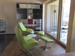Ein modernes Interieur mit einer grünen Sofagarnitur, einem kleinen runden Tisch und einem Bücherregal.
