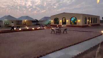 Pátio de hotel com área de estar ao ar livre e um edifício com janelas em arco.