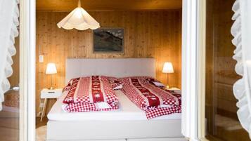 Une chambre avec un lit, deux lampes de chevet, un luminaire suspendu et un tableau encadré au mur.