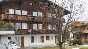 Un immeuble à plusieurs étages, doté d’une façade en bois, de balcons et d’un arbre au premier plan.