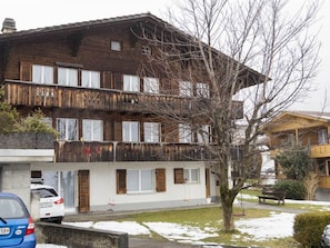 Ein mehrstöckiges Gebäude mit Holzfassade, Balkonen und einem Baum im Vordergrund.