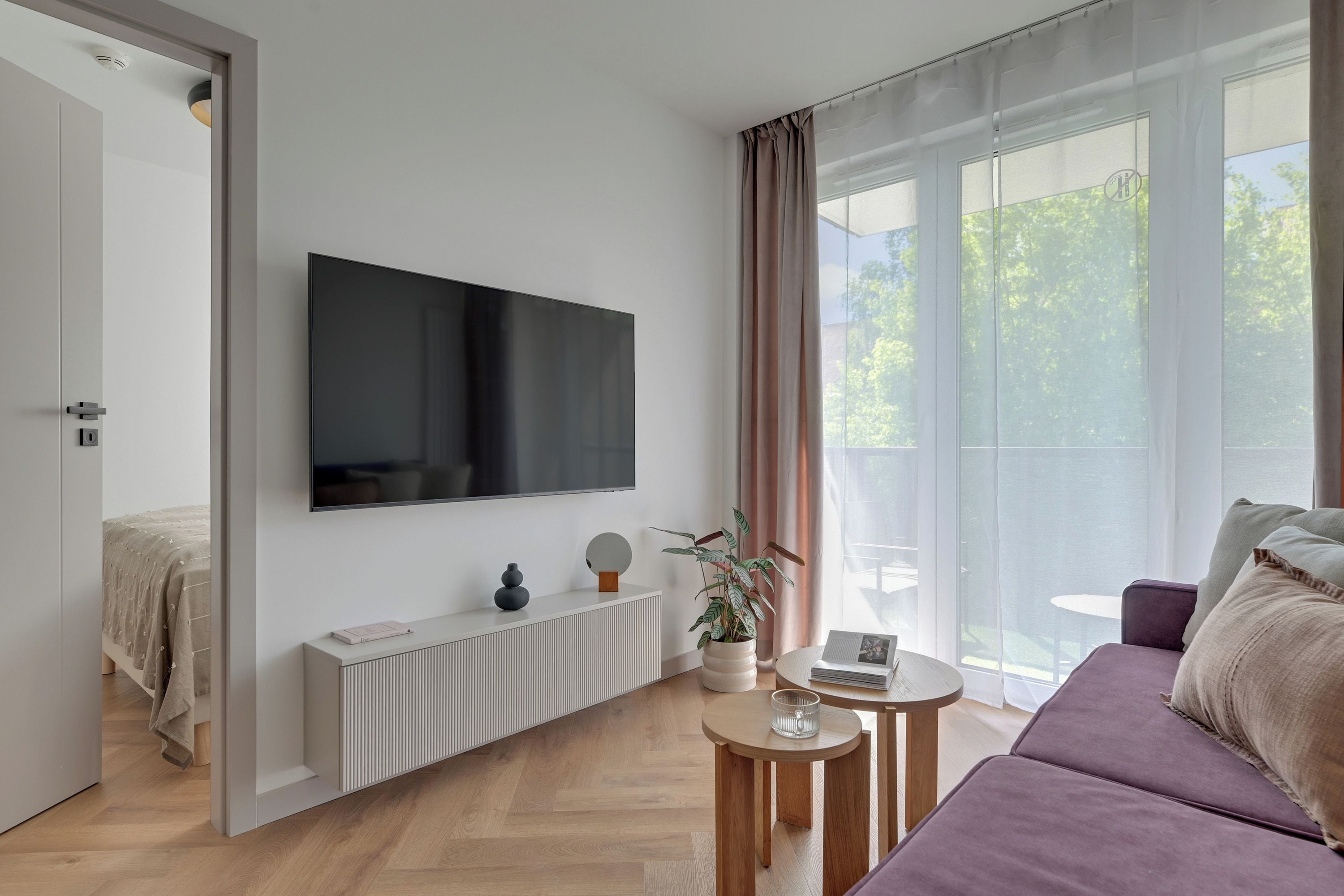 Ein modernes Wohnzimmer mit Flachbildfernseher, einer Couch, einem Couchtisch und einem Topfpflanzen.