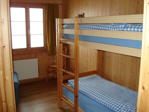 Habitación con literas, ventana, una silla y un radiador.