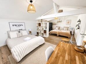 Un dormitorio moderno con una cama grande, una mesita de noche, una mesa de comedor de madera y una estantería empotrada.