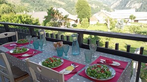 Een eettafel buiten gedekt met salades, blauw glaswerk en brood.