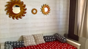 A room with a bed, a window with curtains, and wall-mounted decorative sun shapes. - HARMONIE ROOM FOR 4 PEOPLE (Auris)
