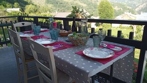 Een buitentafel gedekt met tafelkleden met hartjesprint, blauw en groen servies, en een saladeschaal.
