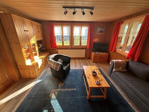 A cozy living room with a sofa, a coffee table, a TV, and a fireplace. - Ferienwohnung Gehrihorn Appartement/Fewo, Dusche, WC, 2 Schlafräume by Interhome (Frutigen)