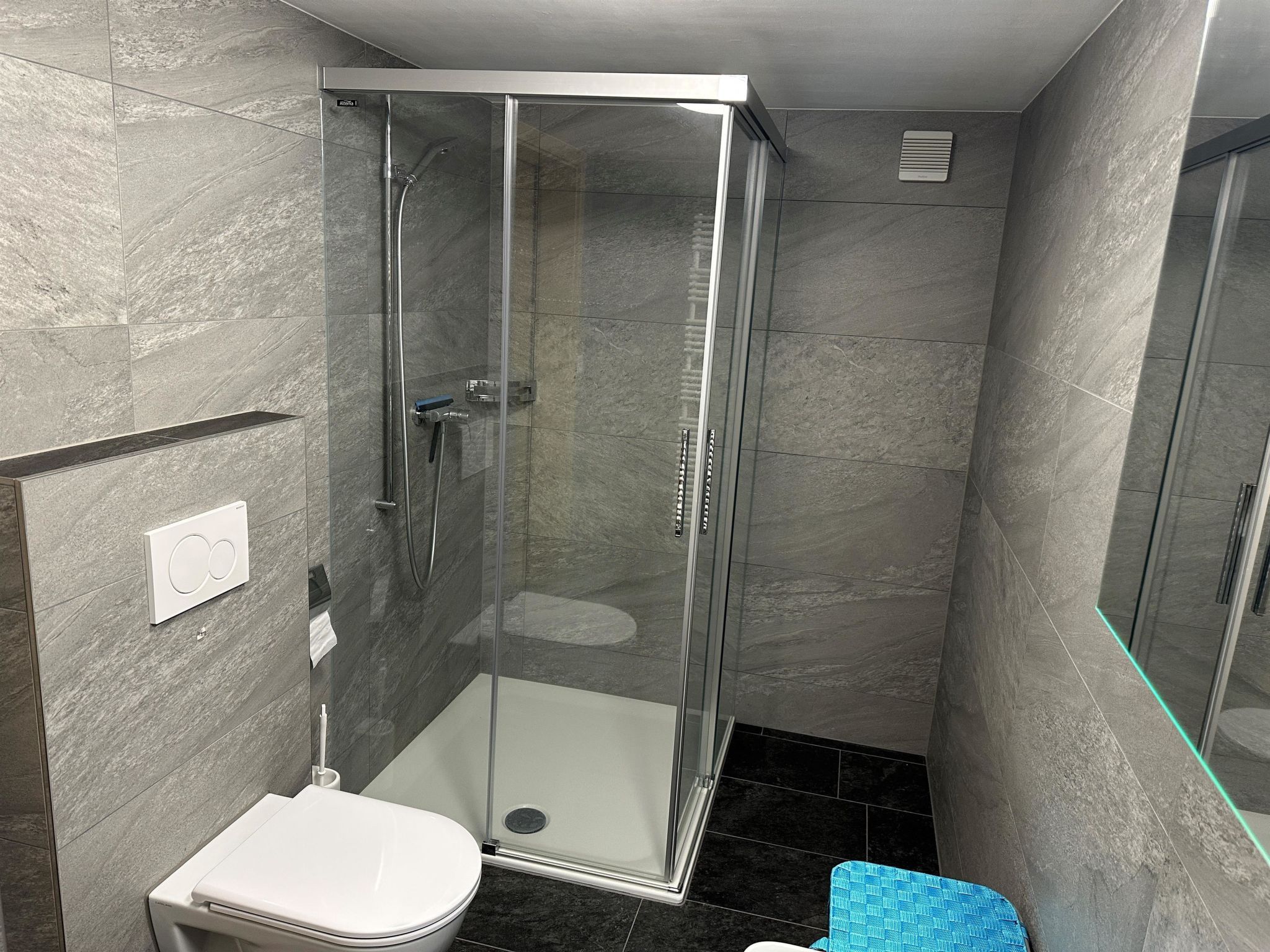A modern bathroom with a glass-enclosed shower, a toilet, and a towel rack.