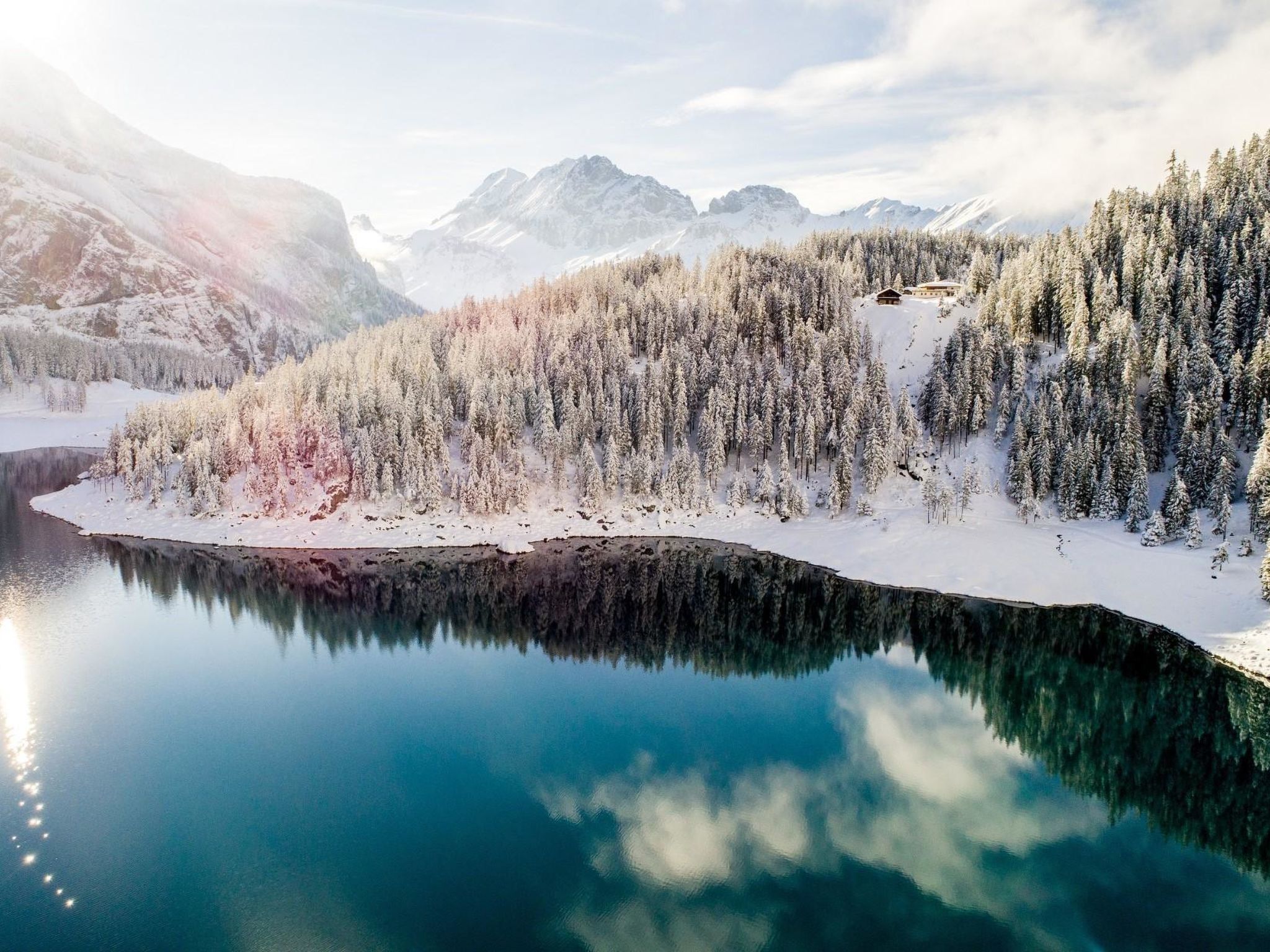 Een vredig winterlandschap met een helder meer dat het omliggende, met sneeuw bedekte bos en de bergen weerspiegelt.