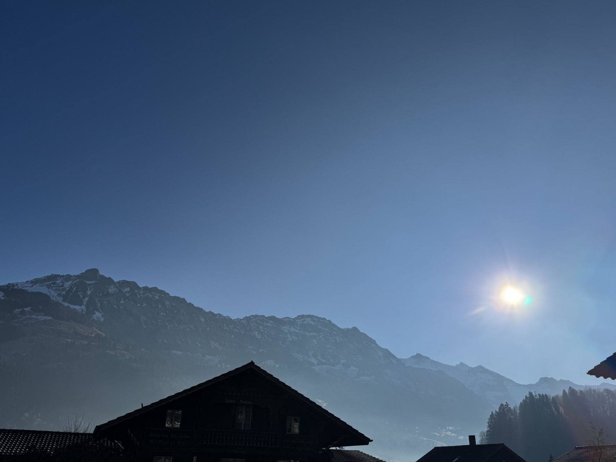 Eine Berglodge mit freiem Blick auf schneebedeckte Gipfel im Hintergrund.