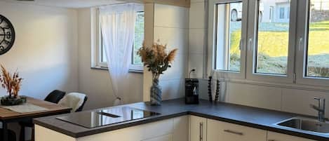 Una cocina moderna con una isla central, muebles blancos y piso de madera.
