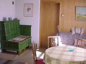 Ein Zimmer mit einer grünen Kommode, einem Tisch mit kariertem Tuch, einer Tür und einem Bild an der Wand.