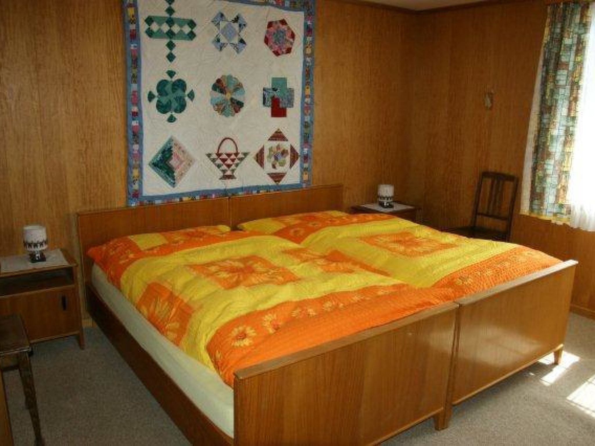 Ein Schlafzimmer mit einem hölzernen Bett, einer Steppdecke, einem Nachttisch und einer Wanddekoration.