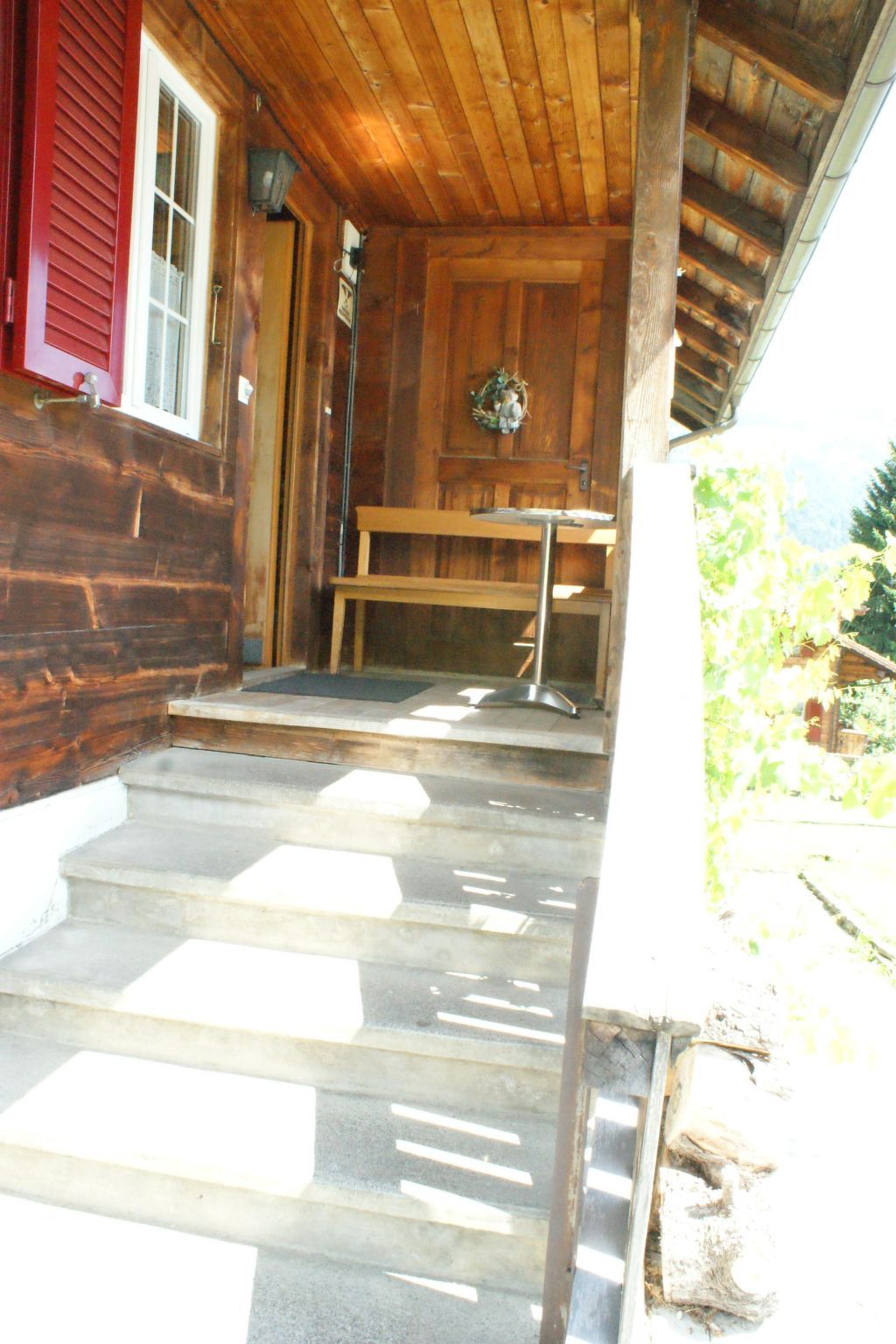 Eine Holzhütte mit Veranda, Bank und Tisch.
