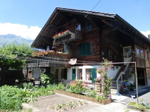 Un chalet en bois doté d’un balcon, d’un jardin et surplombant les montagnes.