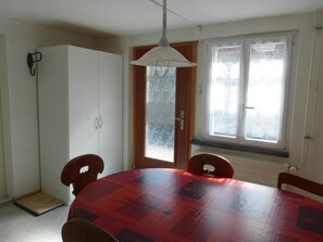 Ein Essbereich mit rundem Tisch, Stühlen, einem Schrank und einem Fenster mit Vorhängen.
