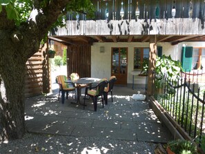 Eine Terrasse im Freien mit Tisch und Stühlen, einem Holzzaun und einem Baum.