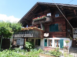 Un chalet de madera con balcón, jardín y fachada blanca.