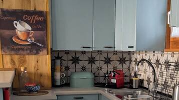Une cuisine avec des meubles de couleur bleu clair, une décoration murale sur le thème du café, une machine à café et un pare-feu décoratif.